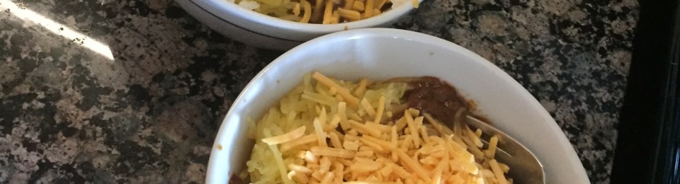 Two bowls of "spaghetti" piled high with chili and cheese.