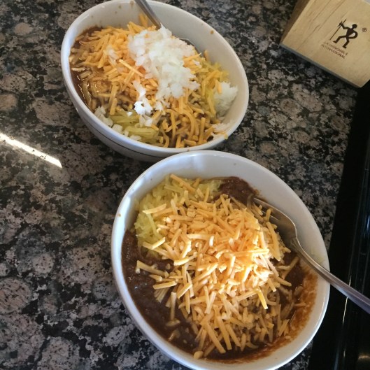 Two bowls of "spaghetti" piled high with chili and cheese. 